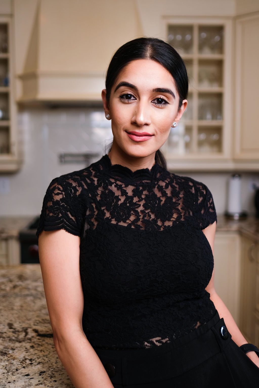 Woman in black lace top leaning on a kitchen counter