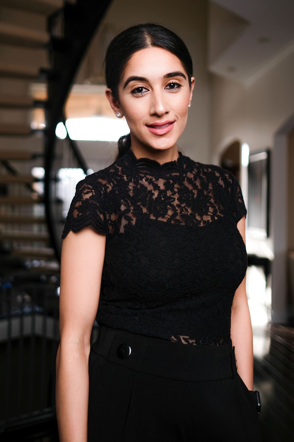 Woman in black lace standing by a spiral staircase